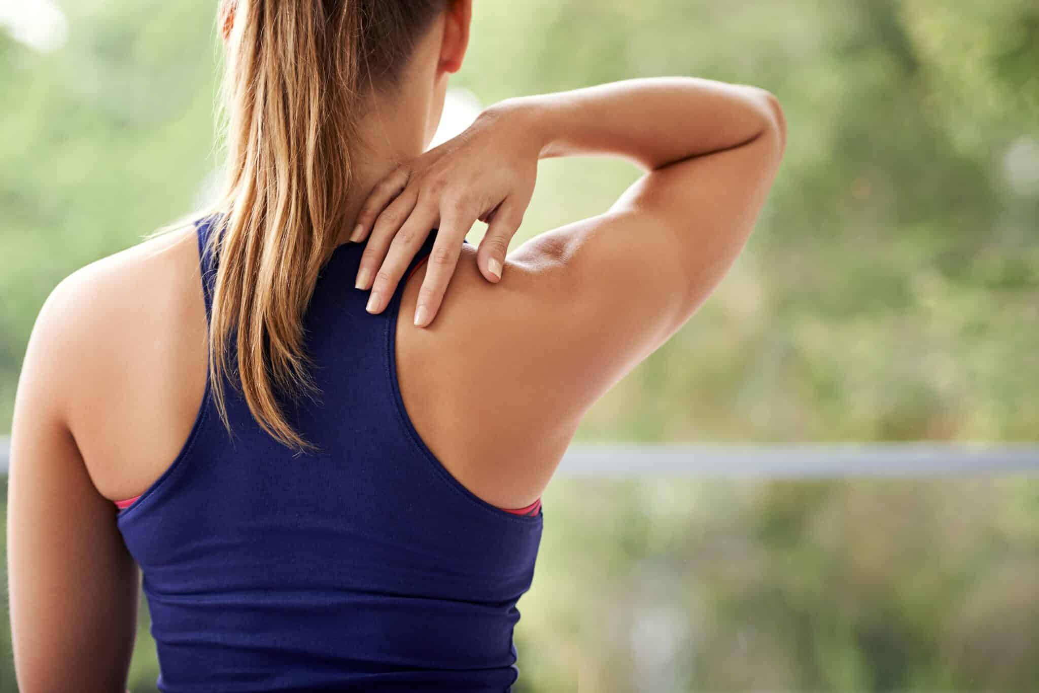 Person holding painful shoulder demonstrating common shoulder pain causes including rotator cuff tears and impingement