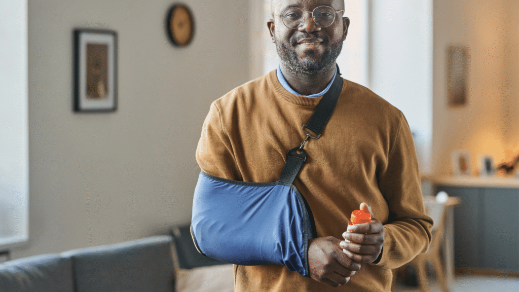 Smiling Black man in shoulder sling at home highlighting how to speed up shoulder surgery recovery