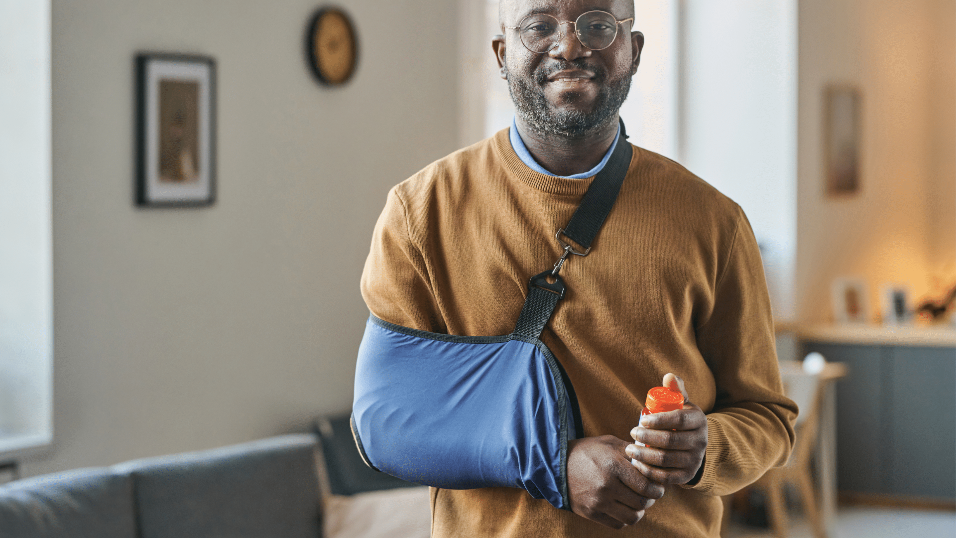 Smiling Black man in shoulder sling at home highlighting how to speed up shoulder surgery recovery