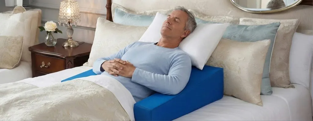 Senior man sleeping peacefully in bed with Restore You shoulder surgery recovery pillow - comfortable post-operative rest