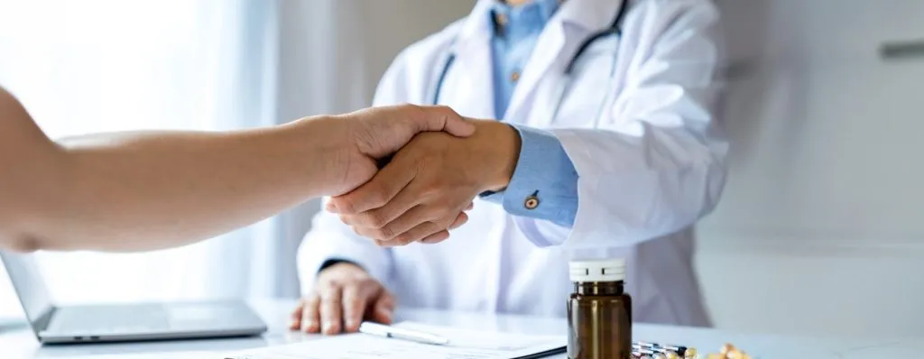 Orthopedic surgeon shaking hands with patient - doctor recommended Restore You therapeutic support for shoulder surgery