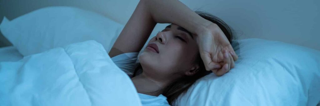 Woman struggling with sleep pain in bed at night after surgery seeking best alternative to recliner after surgery solution