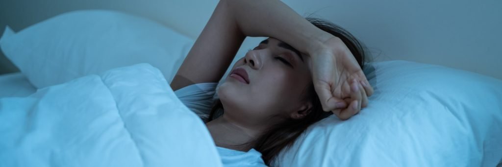 Woman struggling with sleep pain in bed at night after surgery seeking best alternative to recliner after surgery solution